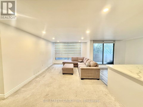 A spacious living room with a large window and a sectional sofa.
