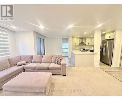 A spacious living room with a large sectional sofa and a kitchen area in the background.