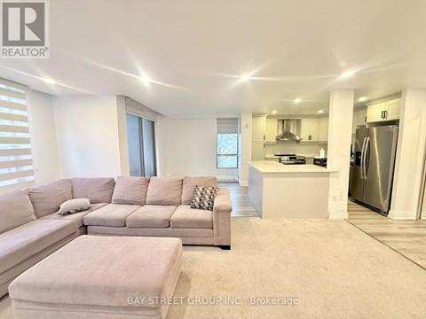 A spacious living room with a large sectional sofa and a kitchen area in the background.