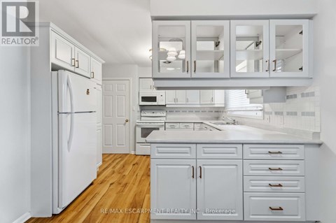 A white kitchen with wooden floors and white cabinets.