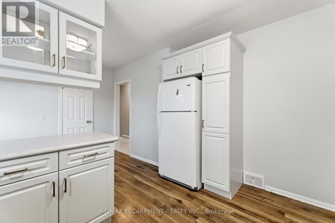 A white refrigerator is in a kitchen with white cabinets.