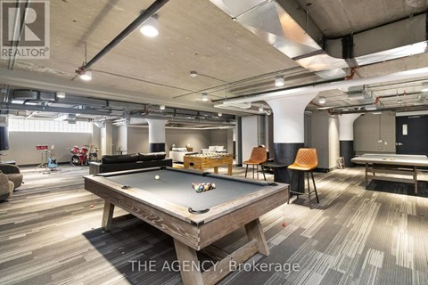 A billiard table is in the middle of a room with a pool table and a ping pong table.