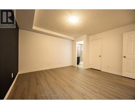 A spacious room with wooden flooring and white walls.