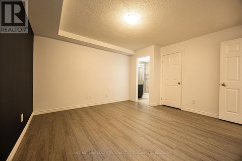A spacious room with wooden flooring and white walls.