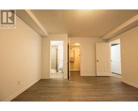 A realtor photo of a white bedroom with wood floors and a doorway leading to a bathroom.