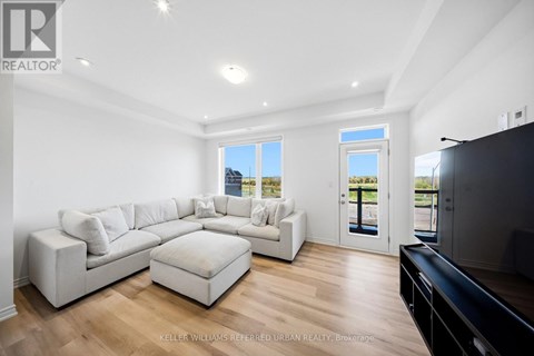 A spacious living room with a white sofa set and a black television.
