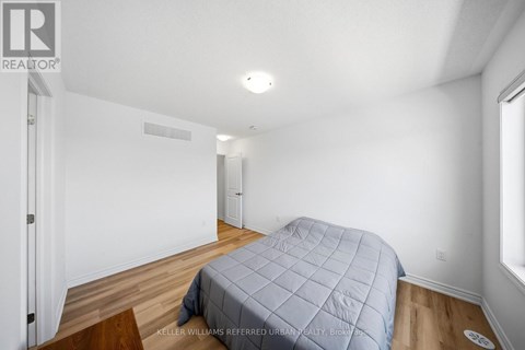 A bedroom with a bed covered in a blue quilted bedspread.