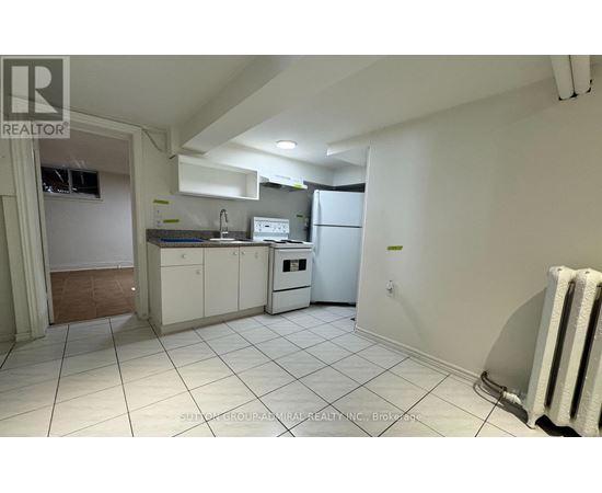 A kitchen with white cabinets and appliances in a room with white walls and tile flooring.