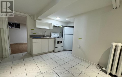 A kitchen with white cabinets and appliances in a room with white walls and tile flooring.