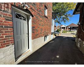 A residential street with a brick house and a closed grey door.