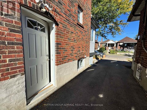 A residential street with a brick house and a closed grey door.