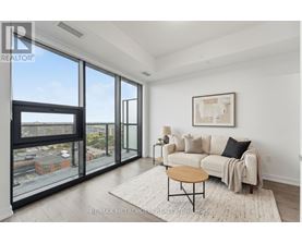 A living room with a couch, a coffee table, and a large window overlooking a cityscape.