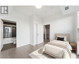 A bedroom with a bed, nightstand, and a window with a view of a balcony.