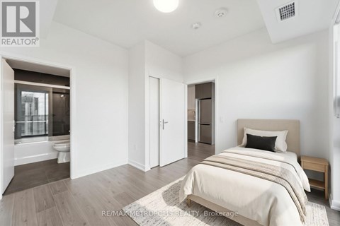 A bedroom with a bed, nightstand, and a window with a view of a balcony.
