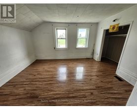 A room with wooden floors and two windows.