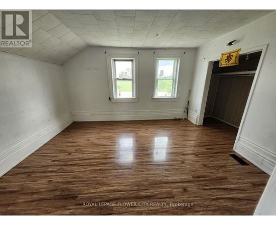 A room with wooden floors and two windows.