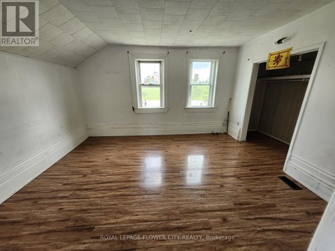 A room with wooden floors and two windows.