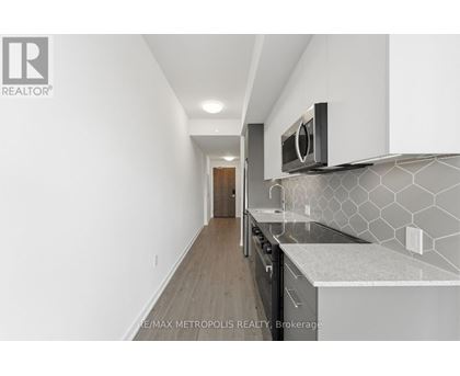 A modern kitchen with white cabinets and a black microwave.