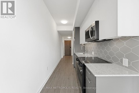 A modern kitchen with white cabinets and a black microwave.