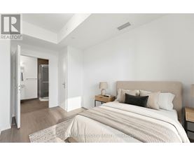 A bedroom with a large bed and a nightstand with a lamp.