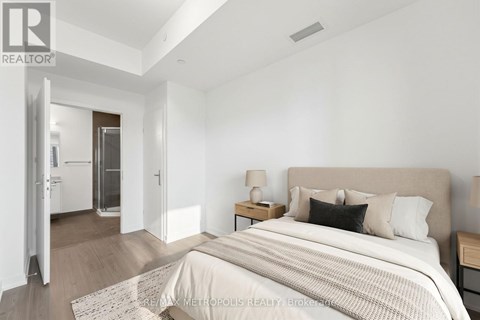 A bedroom with a large bed and a nightstand with a lamp.