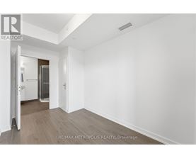 A spacious room with wooden flooring and white walls, with a doorway leading to another room.