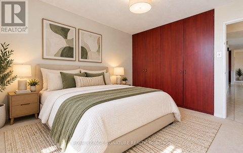 A bedroom with a large bed, two nightstands, and a plant.