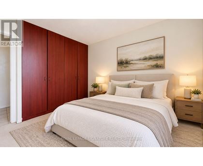 A bedroom with a large bed, two nightstands, and a painting on the wall.