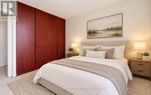A bedroom with a large bed, two nightstands, and a painting on the wall.