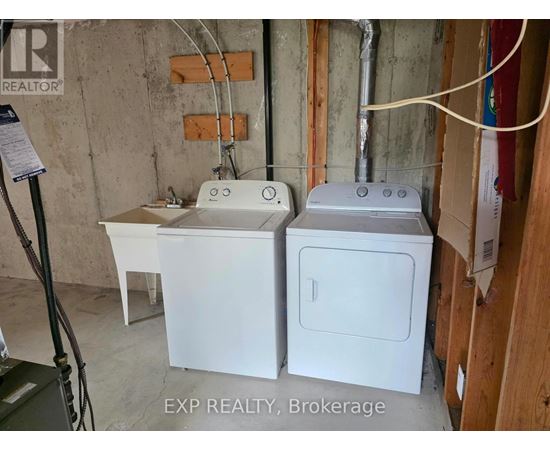 A white washer and dryer are sitting next to each other in a basement.