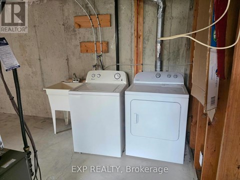 A white washer and dryer are sitting next to each other in a basement.