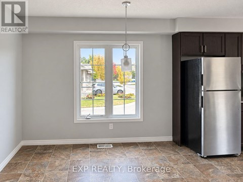 A kitchen with a refrigerator and a window overlooking a street.