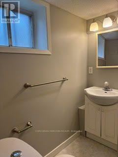 A small bathroom with a toilet, sink, and mirror.