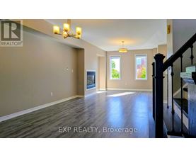 A spacious room with wooden floors and a staircase on the right side.