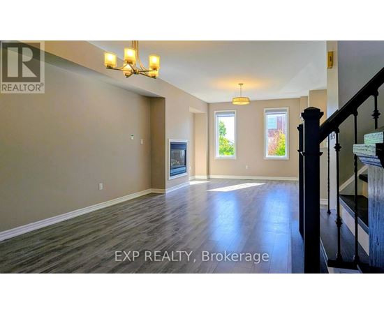 A spacious room with wooden floors and a staircase on the right side.