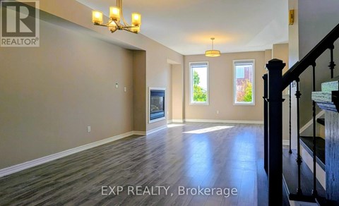 A spacious room with wooden floors and a staircase on the right side.