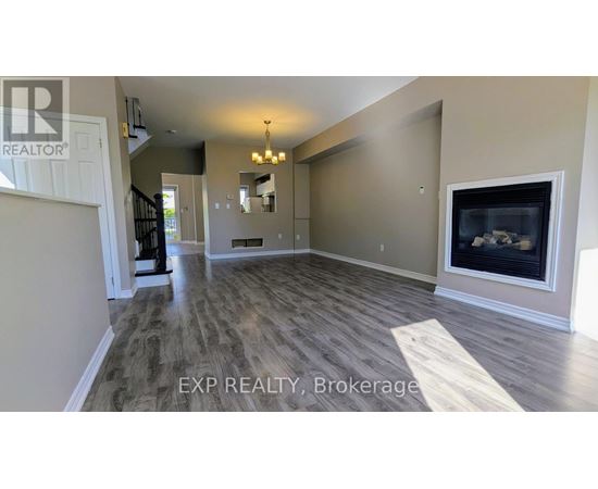 A spacious living room with wood flooring and a fireplace.
