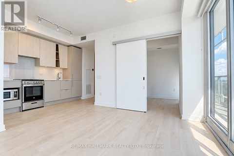 A spacious kitchen with wooden floors and white walls.