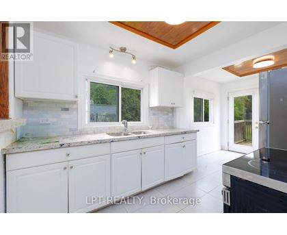 A kitchen with white cabinets and a wooden ceiling.