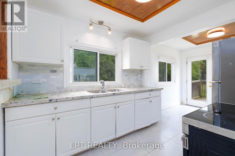 A kitchen with white cabinets and a wooden ceiling.