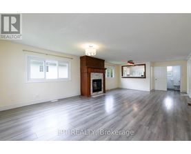 A spacious living room with wood flooring and a fireplace.