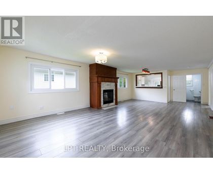 A spacious living room with wood flooring and a fireplace.