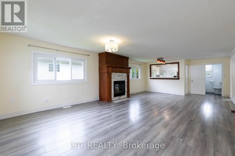 A spacious living room with wood flooring and a fireplace.