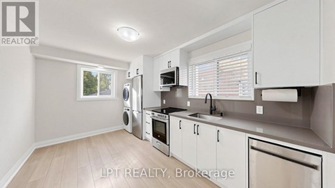 A modern kitchen with white cabinets and stainless steel appliances.