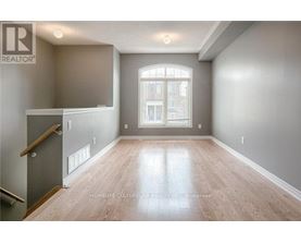 A spacious room with wooden flooring and a large window.
