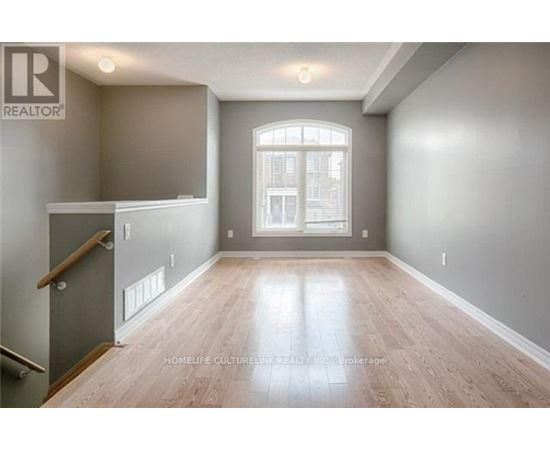 A spacious room with wooden flooring and a large window.