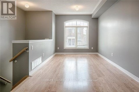 A spacious room with wooden flooring and a large window.
