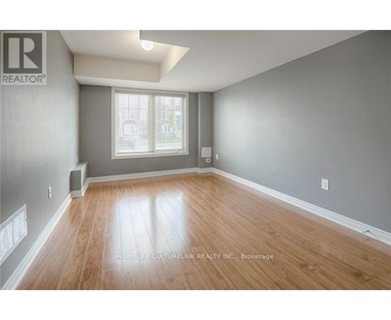 A spacious room with wooden flooring and a window.