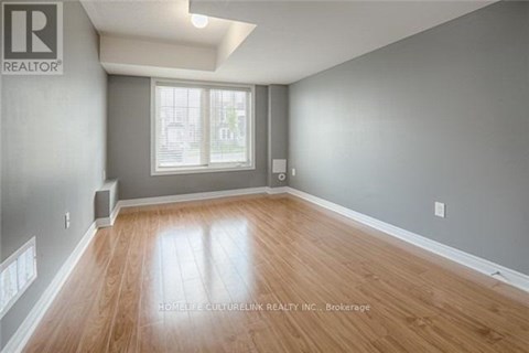A spacious room with wooden flooring and a window.