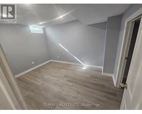 A room with wooden flooring and a door on the right side.